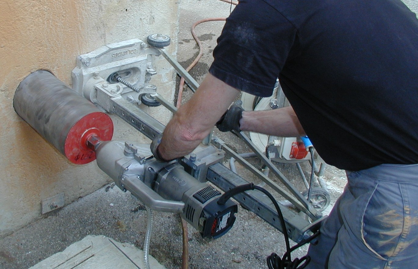 Illustrative photograph of a rig-mounted diamond core drill entering a masonry wall