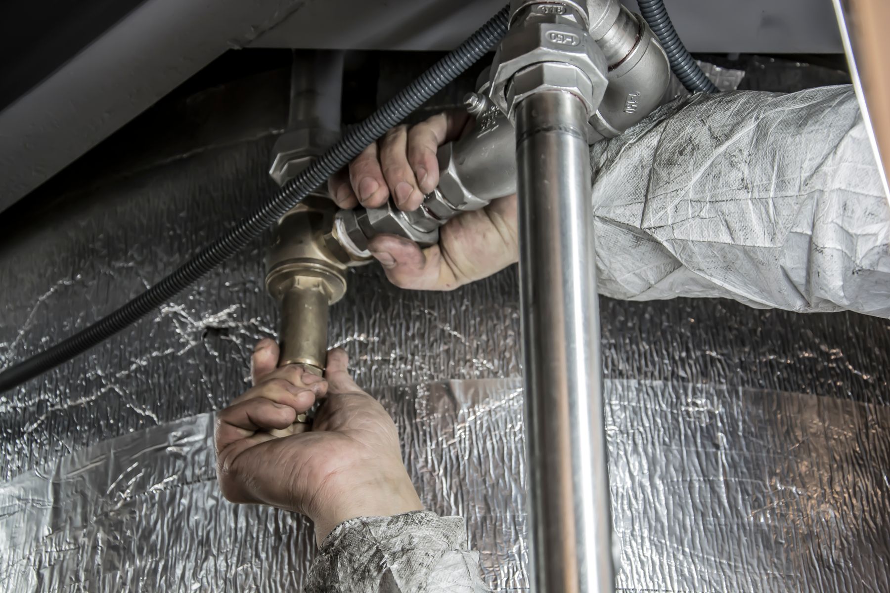 Hands carrying out plumbing work on metal pipework